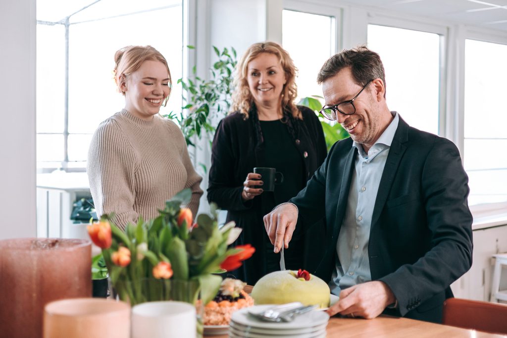 Glada medarbetare som skär upp en bit tårta i Didups fikarum.